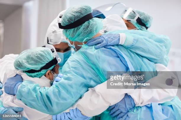 ärzte und krankenschwestern umarmen sich während der pandemie - essenzielle berufe und dienstleistungen stock-fotos und bilder
