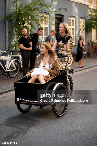 Mie Juel wearing knitted brown dress,white bag and Marie Hindkær wearing withe and brown checked dress in Christiania bike outside Ganni during...