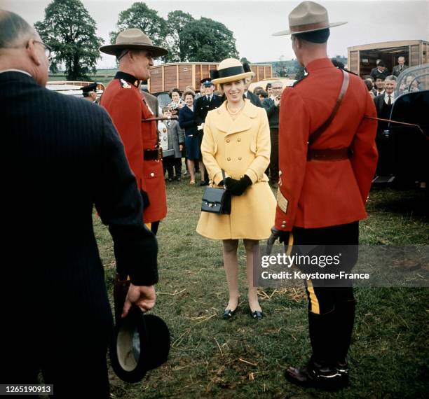 La princesse Anne, portant un chapeau à large bord, photographiée discutant avec un agent de la police montée canadienne pendant le plus grand salon...