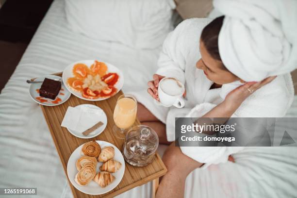 frau trinkt kaffee und isst frühstück im bett - breakfast in bed tray stock-fotos und bilder