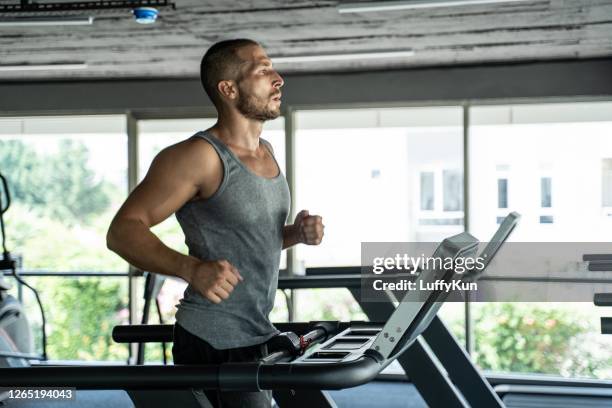 young handsome man doing cardio exercises with treadmill in gym with dumbbell fitness health club - treadmill stock pictures, royalty-free photos & images