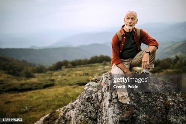 hogere wandelaar die op de bergrots stelt - outdoor guy sitting on a rock stockfoto's en -beelden