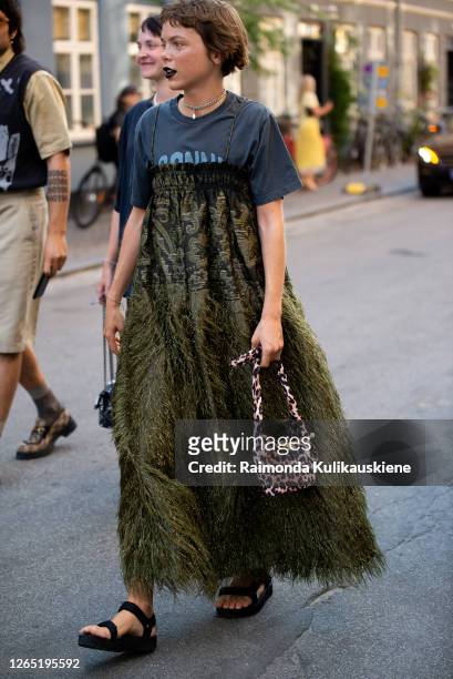 Emma Fridsell outside Ganni wearing grey t-shirt, long dark green dress with feathers and Ganni animal print bag during Copenhagen fashion week SS21...