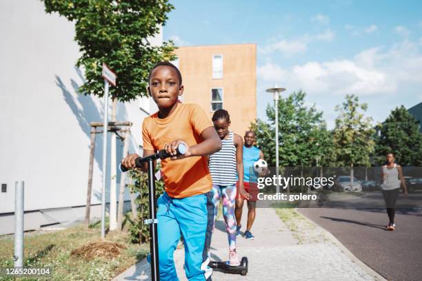famille dans la rue en direction du terrain de sport - quartier photos et images de collection