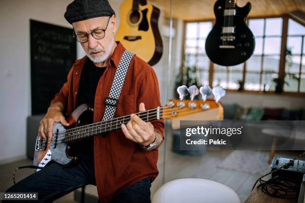 chitarrista rock senior che suona la chitarra nel suo studio di casa - basso foto e immagini stock