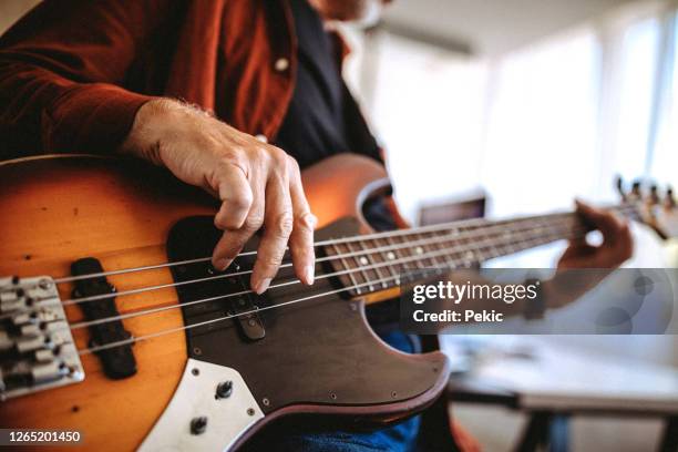 musicista senior che suona il basso in uno studio musicale - electric guitar foto e immagini stock