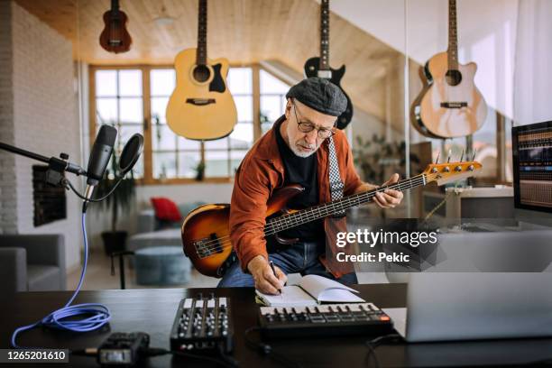 hogere musicus met gitaar het schrijven op een muziekblad - componist stockfoto's en -beelden