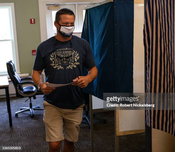 Local resident wearing a mask exits a voting booth after casting his ballot in the Vermont Primary Election on August 11, 2020 in Charlotte, Vermont....