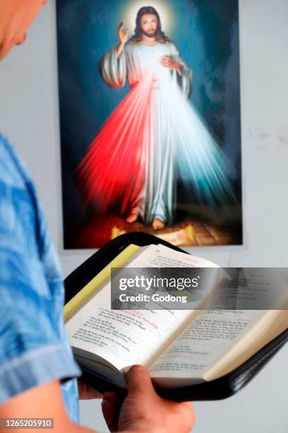 Jesus the Divine Mercy, I trust in you. Man reading the bible. Close-up. Ho Chi Minh City. Vietnam.