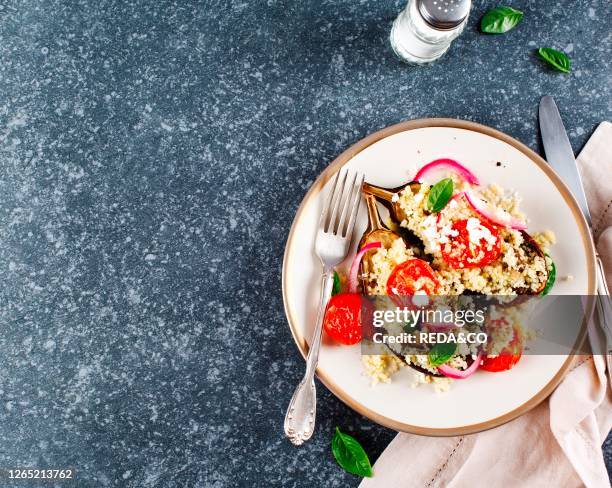 Baked eggplant stuffed with couscous. Tomatoes. Feta and basil leaves. Top view. Copy space.