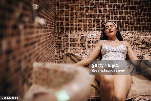 één aantrekkelijke jonge vrouw die in de stoomruimte ontspant - turks bad stockfoto's en -beelden