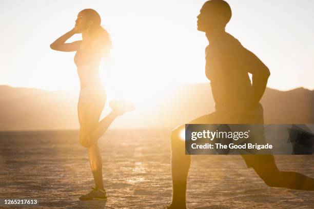 couple stretching in desert against sky - woman stretching sunset stockfoto's en -beelden