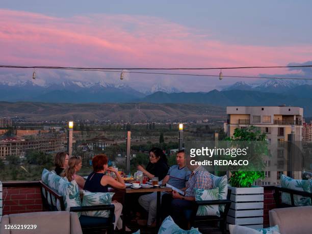 Locals having dinner in an open air restaurant on top of a high rise building. The capital Bishkek located in the foothills of Tien Shan. Asia....
