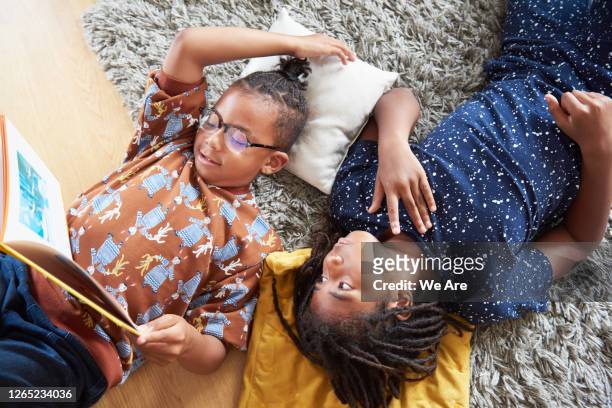 overhead of brothers reading while lying on floor - reading stock pictures, royalty-free photos & images