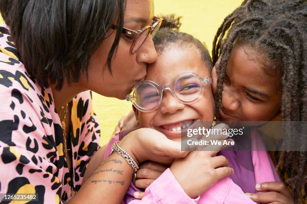 close up of boy being kissed by mother and brother - fashionable glasses stock pictures, royalty-free photos & images