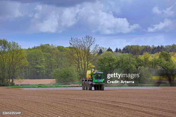 Farmer spraying pesticides / insecticides / weed killer / herbicide over field / farmland in spring.