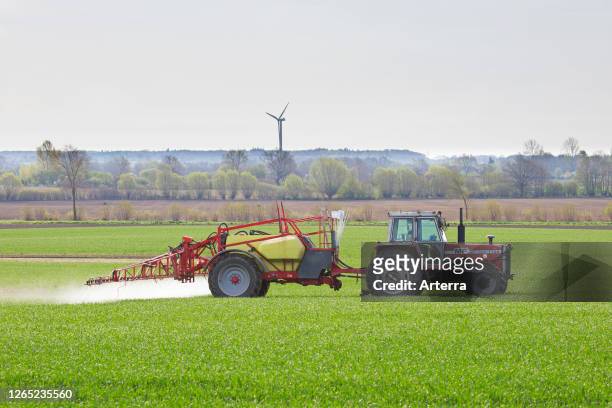 Farmer spraying pesticides / insecticides / weed killer / herbicide over field / farmland in spring.