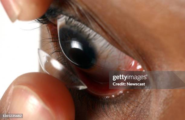 Facial close up of a young man putting a contact lens onto his eye..