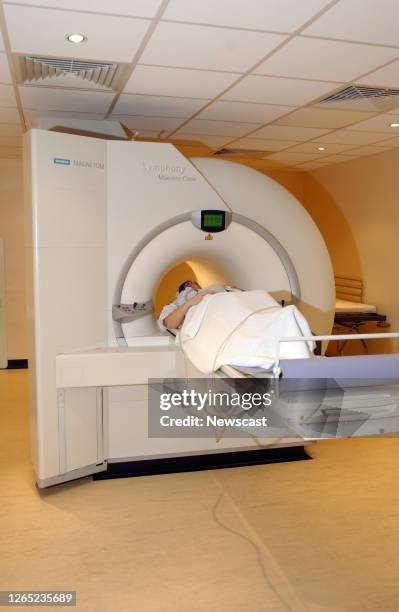 Female patient lies on the examination table of a magnetic resonance imaging scanner which is primarily used to visualize body structure and...