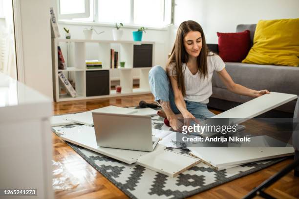 donna sta assemblando mobili a casa - mobilio foto e immagini stock