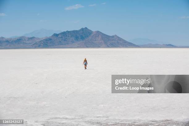 Woman walks across Bonneville Salt Flats in Tooele County in Utah.