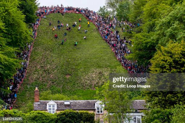 Participants chase a wheel of cheese during the annual cheese rolling event on Cooper's Hill in Brockworth in Gloucestershire.