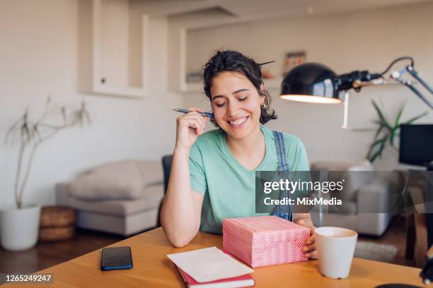 girl writing a gift card for someone who she wants to send a care package - care package stock pictures, royalty-free photos & images