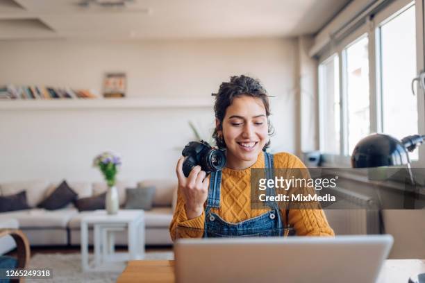 young photographer working on her photos at her home office - fotógrafos imagens e fotografias de stock