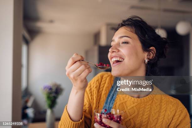 portrait of a happy girl enjoying fresh pomegranate at home - pomegranate stock pictures, royalty-free photos & images