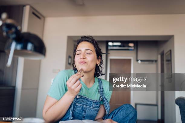 mädchen genießen ihre lieblings-cookie zu hause - beißen stock-fotos und bilder