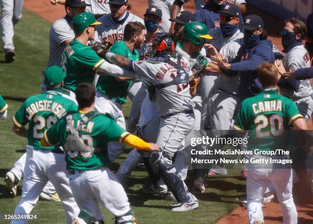 The Oakland Athletics and the Houston Astros benches scuffle after Athletics' Ramon Laureano charged Houston hitting coach Alex Cintron in the...