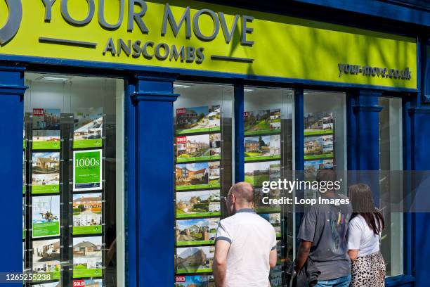 People looking at houses for sale or rent in an estate agents window.