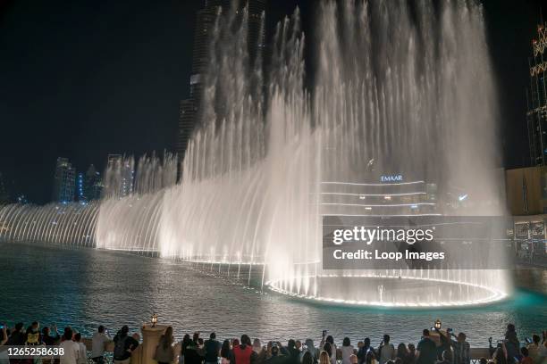 Crowds raise their phones to capture the stunning dancing fountain show in Dubai.