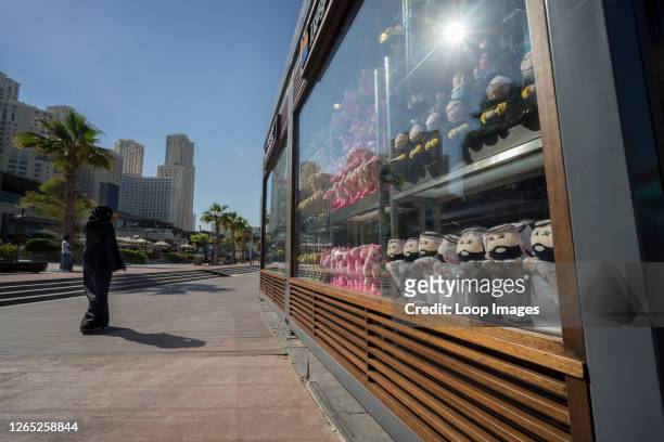 Woman walks past a shop window filled with Arabic souvenirs in Dubai.