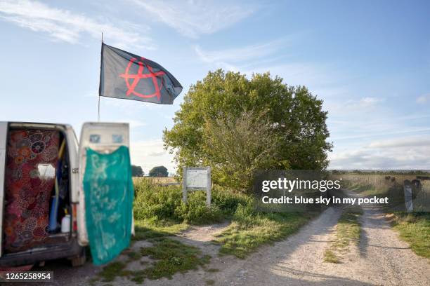 an anarchy flag blowing in the wind on top of a van on the ridgeway bridal path in wiltshire, england on a summer evening. - símbolo da anarquia imagens e fotografias de stock