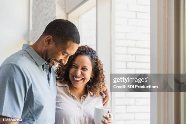 happy couple enjoy a quiet moment at home together - mid adult couple stock pictures, royalty-free photos & images