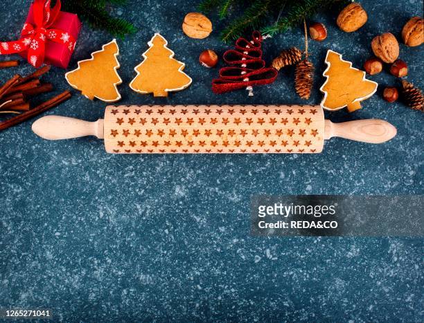 Christmas baking concept. Gingebread cookies, rolling pin, gift box, cinnamon and holiday decoration. Top view. Copy space.