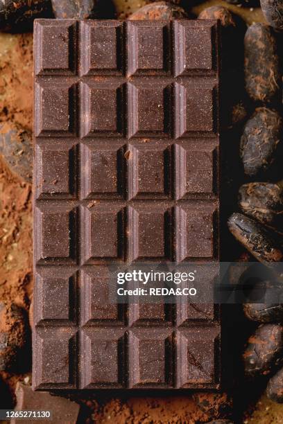 Dark chocolate bar with cocoa beans, cocoa powder. Food background. Flat lay, close up.
