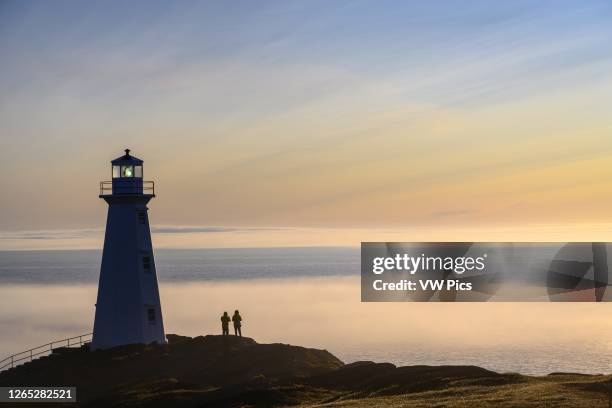 Visitors at Cape Spear Lighthouse with fog bank over the Atlantic Ocean; St. John's, Newfoundland, Canada.