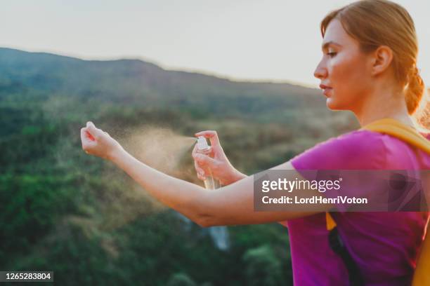woman using anti mosquito spray outdoors at hiking trip - fly spray stock pictures, royalty-free photos & images