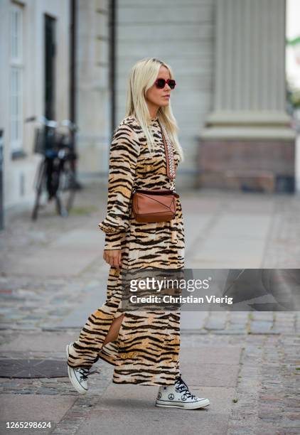 Guest is seen wearing brown Loewe bag, dress with tiger print outside Baum und Pferdgarten during Copenhagen Fashion Week Spring/Summer 2021 on...