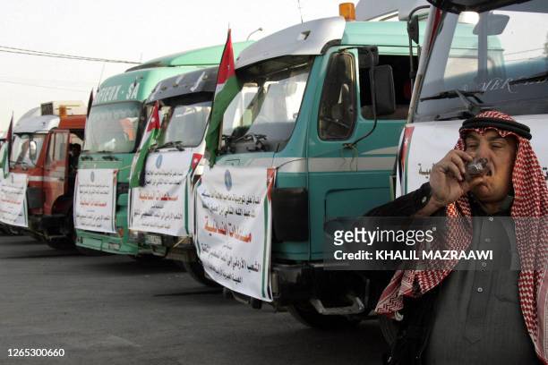 Driver drinks tea in front of trucks loaded with humanitarian aid at the King Hussein Bridge crossing in Amman, before departing for the Gaza Strip...