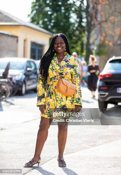 Lois Opoku is seen wearing yellow dress with floral print, brown Dior bag outside Samsøe & Samsøe during Copenhagen Fashion Week Spring/Summer 2021...