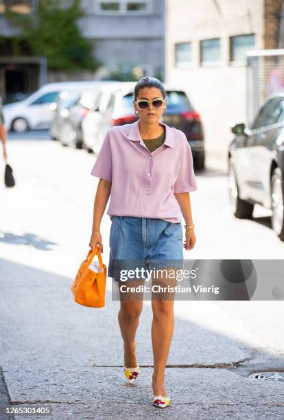 Guest wearing denim shorts, rose shirt, orange bag is seen outside Samsøe & Samsøe during Copenhagen Fashion Week Spring/Summer 2021 on August 11,...