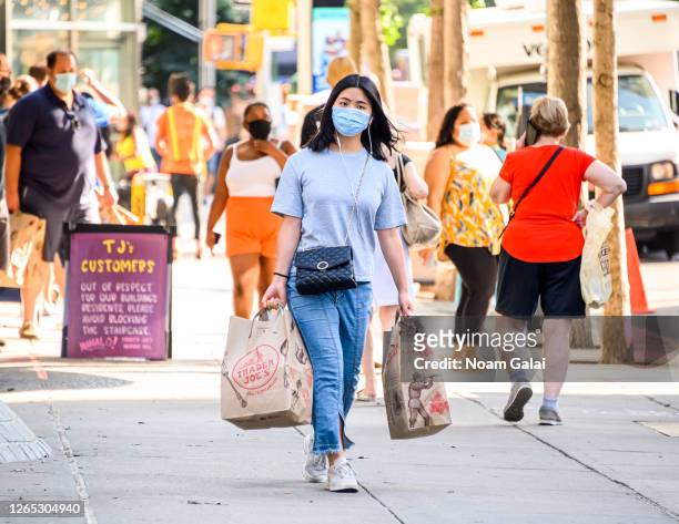 Person wears a protective face mask while carrying grocery bags outside Trader Joe's in Kips Bay as the city continues Phase 4 of re-opening...