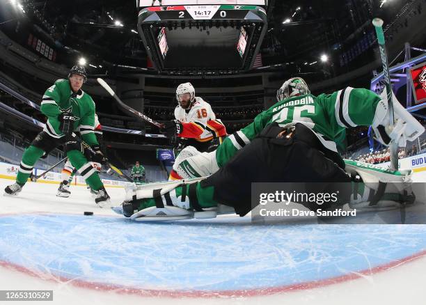 Goaltender Anton Khudobin of the Dallas Stars makes a save as Miro Heiskanen of the Dallas Stars and Michael Stone of the Calgary Flames look to the...