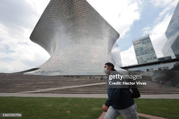 Person wearing a mask walks outside the Soumaya museum on August 11, 2020 in Mexico City, Mexico. Despite Mexico City government allowed museums to...