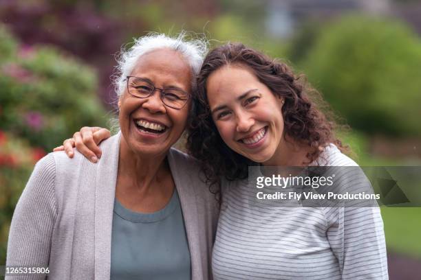 mixed race mother and daughter walk and talk together outside - adult stock pictures, royalty-free photos & images