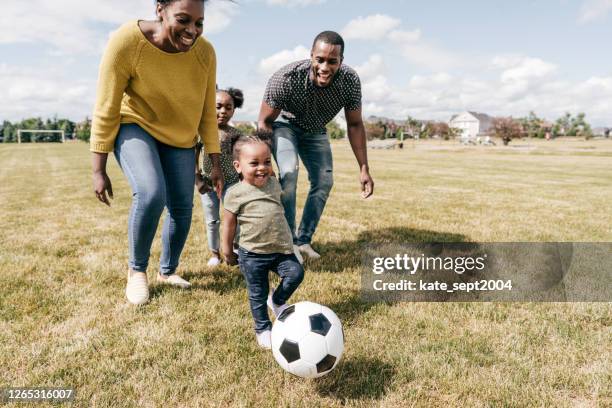 gelukkige familiemomenten - jonge geitjes die voetbal met ouders spelen - mother running stockfoto's en -beelden