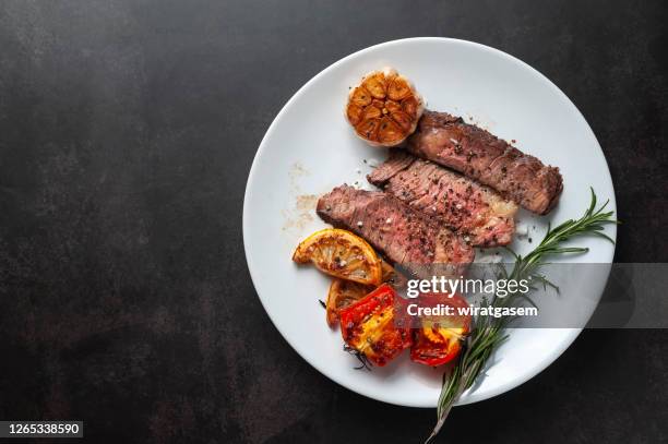 sliced grilled wagyu steak served on white plate with grilled sliced lemon, tomatoes, garlic and rosemary. - roast beef stock pictures, royalty-free photos & images